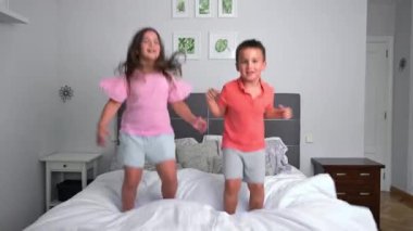 Yatakta zıplayan neşeli kardeşler. Yüksek kalite 4k görüntü