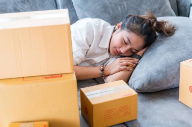 Güzel Asyalı kadınlar kanepelerde uyurlar. Küçük işletmeleri olan bir sürü paket kutuyla. Müşterilere internet üzerinden satış yaparlar..