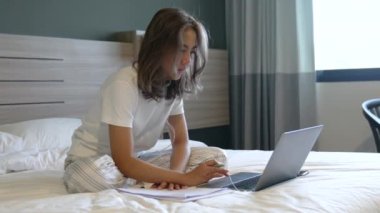 Yatakta dizüstü bilgisayarı ve kredi kartıyla güzel Asyalı kadınlar, internetten alışveriş yapıyor, faturaları ödüyor, sabahları bilet alıyor. Sabah rahatlama zamanı online alışveriş için