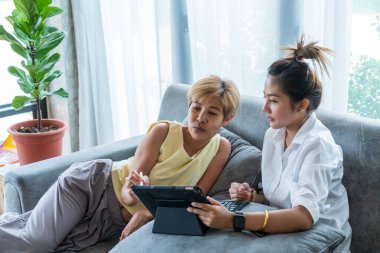 Büyükannen ve torunun kanepede tablet oynuyorlar. Bilgi alışverişi ve hayat hikayeleri. Oturma odasında rahatla..