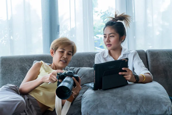 Grandma and grandson play the tablets on the sofa. Exchange knowledge and life stories. relax in living room.