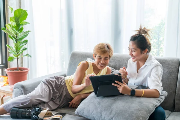 Grandma and grandson play the tablets on the sofa. Exchange knowledge and life stories. relax in living room.