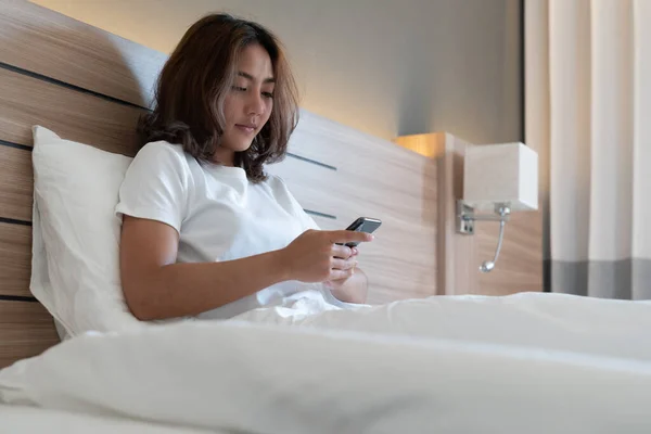 Young asian women lying in bed texting and checking social apps in smartphone on bed before after she sleeping at night. Mobile addict concept.