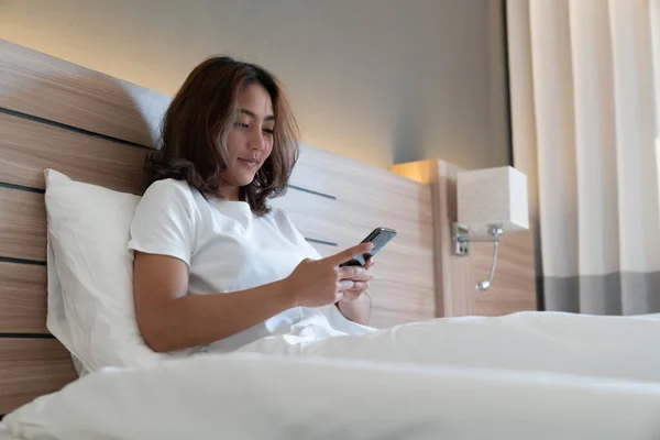 Young asian women lying in bed texting and checking social apps in smartphone on bed before after she sleeping at night. Mobile addict concept.