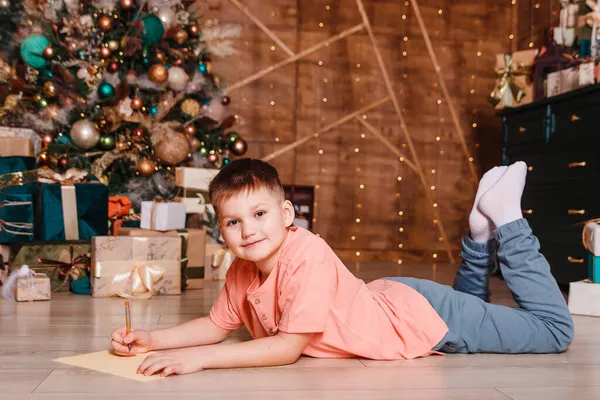 Åttaårig Pojke Ligger Magen Och Skriver Bladverket Julrummet — Stockfoto