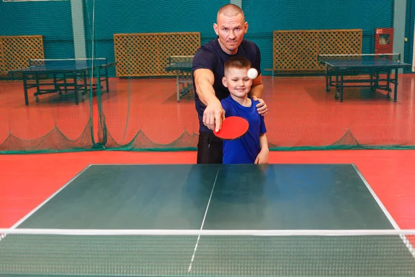 the coach teaches the Igart and table tennis. practice of the blow in table tennis.father and son