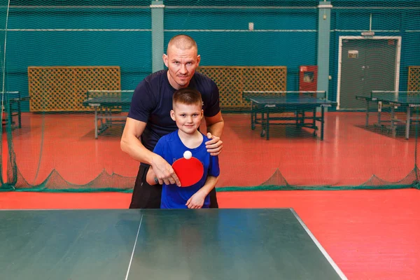 the coach teaches the Igart and table tennis. practice of the blow in table tennis.father and son