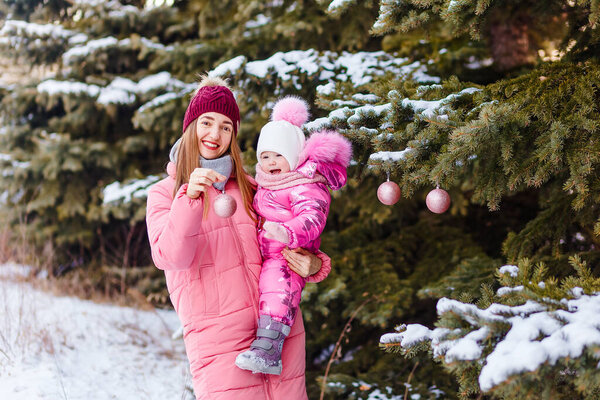 happy woman in pink down jacket hugs a little girl in winter