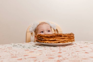 İki yaşında bir kız krep ısırıyor. Maslenitsa festivali