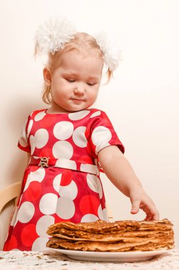 İki yaşında bir kız ve büyük bir tabak krep. Maslenitsa tatili. gözleme ve çocuklar