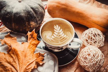 Kahverengi arka planda, balkabaklı bir fincan kahve.