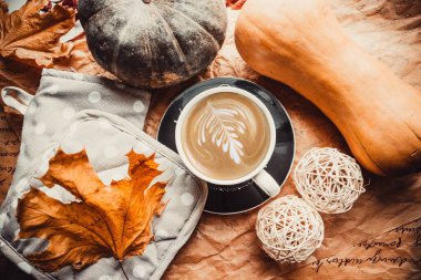 Cup of coffee on wooden brown background with pumpkins and leaves