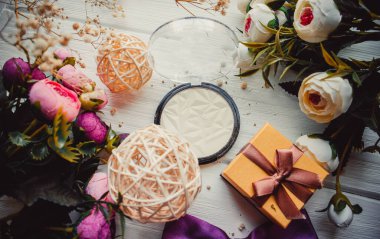 Makyaj için fosforlu kalem ve ahşap arkaplanda çiçekler.