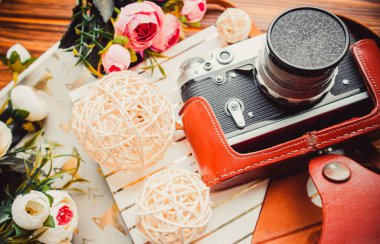 Camera and flowers on wood background with notepads