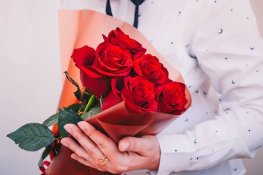 Beautiful bouquet of red roses on a white background with green leaves