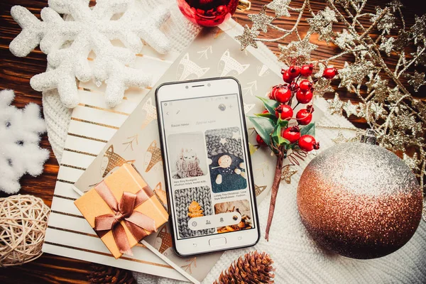 Phone and christmas decorations on a wood brown background with warm sweater