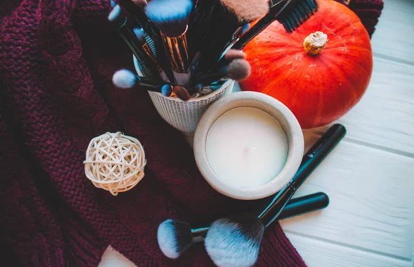 Candle and makeup brushes on wood white background with sweater