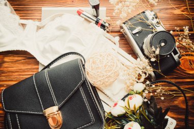 El çantası, retro kamera ve kahverengi arka planda kırmızı rujlu sutyen.