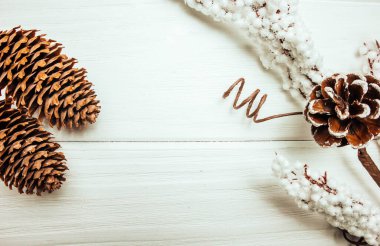 Beyaz ahşap arka planda çam kozalakları ve noel süslemeleri