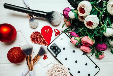 Telefon ve makyaj fırçaları ahşap arka planda Noel süslemeleri ve çiçeklerle