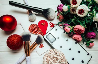 Telefon ve makyaj fırçaları ahşap arka planda Noel süslemeleri ve çiçeklerle