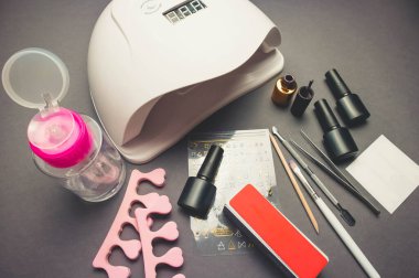 Jel cilası ve aksesuarlı siyah kağıt zemin üzerinde morötesi lamba ve dekor.