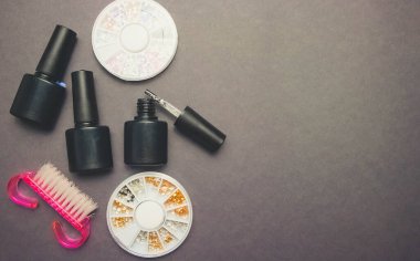 Manikür için aksesuarları olan koyu kağıt zemin üzerine jel cilası ve dekor