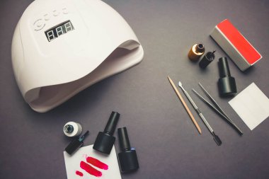 Jel cilası ve aksesuarlı siyah kağıt arkaplanda morötesi lamba ve tırnak törpüsü