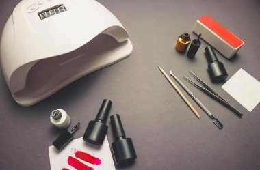 Jel cilası ve aksesuarlı siyah kağıt arkaplanda morötesi lamba ve tırnak törpüsü