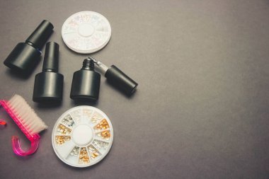 Manikür için aksesuarları olan koyu kağıt zemin üzerine jel cilası ve dekor