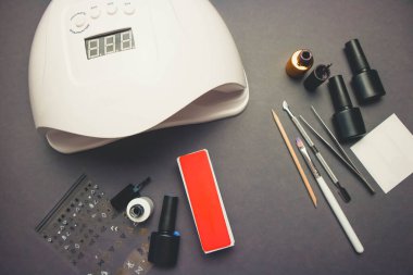 Koyu arkaplanda morötesi lamba ve dekor, jöle cilası ve manikür için fırça.