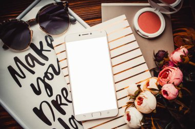 Telefon ve not defterleri kahverengi ahşap arka planda çiçekler ve allık ile