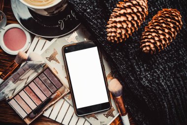 Telefon, not defterleri ve tahta bir arka planda örgü süveter ile çıkıntılar. Model