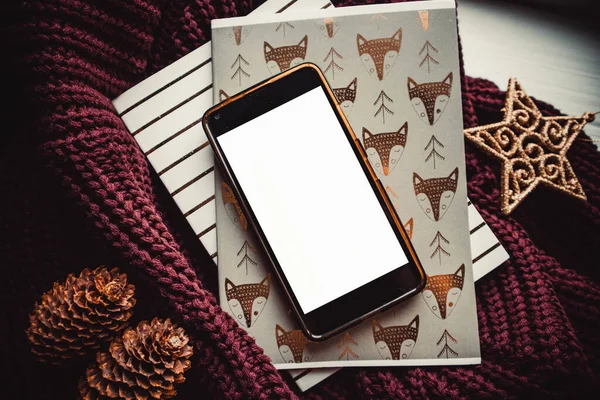 Ahşap arka planda telefon ve not defterleri ve noel süslemeleri. Model