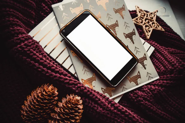 Ahşap arka planda telefon ve not defterleri ve noel süslemeleri. Model