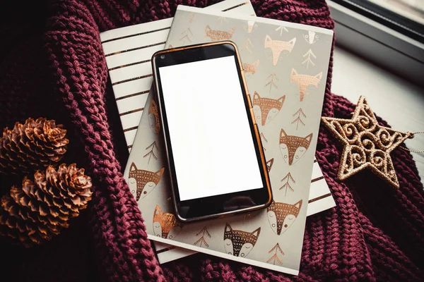 Ahşap arka planda telefon ve not defterleri ve noel süslemeleri. Model