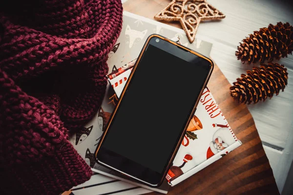 Ahşap arka planda telefon ve not defterleri ve noel süslemeleri. Model