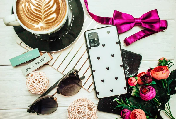 Beyaz arka planda, güneş gözlüğü ve çiçekli bir fincan kahve ve telefon. Flatlay. Bahar fotoğrafçılığı