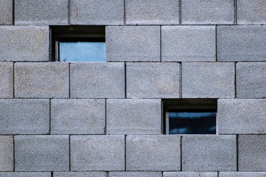 Çimento bloğunun dış duvarında iki farklı kare pencere var. Somut bölümlere sahip alan