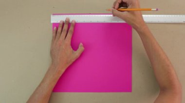 Pembe bir kartpostalın üzerindeki kalemle paralel çizgileri takip ediyorum. Arka planda bir el işi kağıdı yüzeyi var..