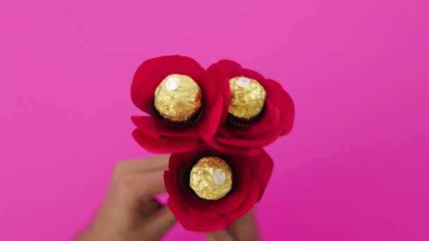 工芸品を作る 中央にチョコレート入りの赤い紙のバラが3本一緒に ピンクの背景 — ストック動画