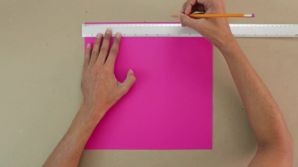 ピンクのカードストックに鉛筆で平行線をトレースします 背景にはクラフト紙の表面 — ストック動画