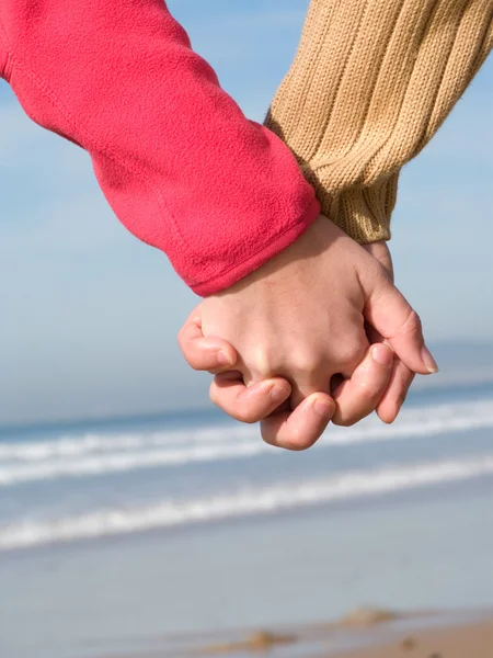 Amantes casal de mãos dadas na praia no inverno — Fotografia de Stock