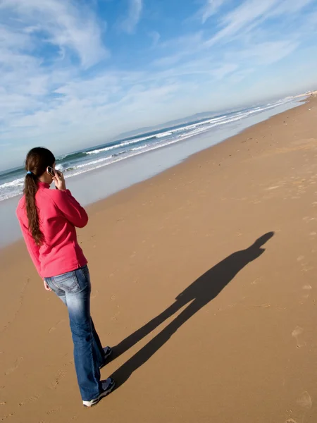 Vrouw wandelen alleen op het strand, praten in een mobiele telefoon — Stockfoto