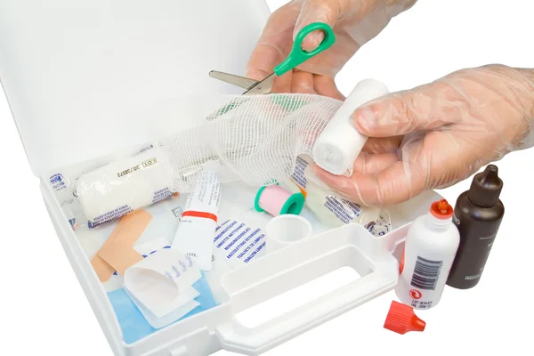 First aid kit and hands with gloves cutting the bandage Stock Photo