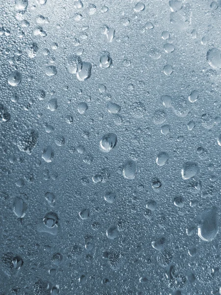Kropelki wody niebieski w tle powierzchni szkła — Zdjęcie stockowe
