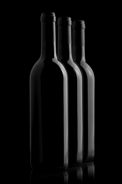 Tres elegantes botellas de vino en un fondo negro — Foto de Stock