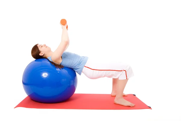 Jovem realizando exercícios de fitness com uma bola de fitness e halteres — Fotografia de Stock