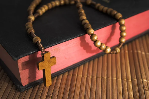Bible s korálky růžence krucifix na tabulku slámy — Stock fotografie