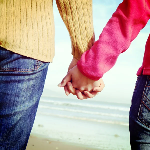 Amantes pareja tomados de la mano en la playa —  Fotos de Stock